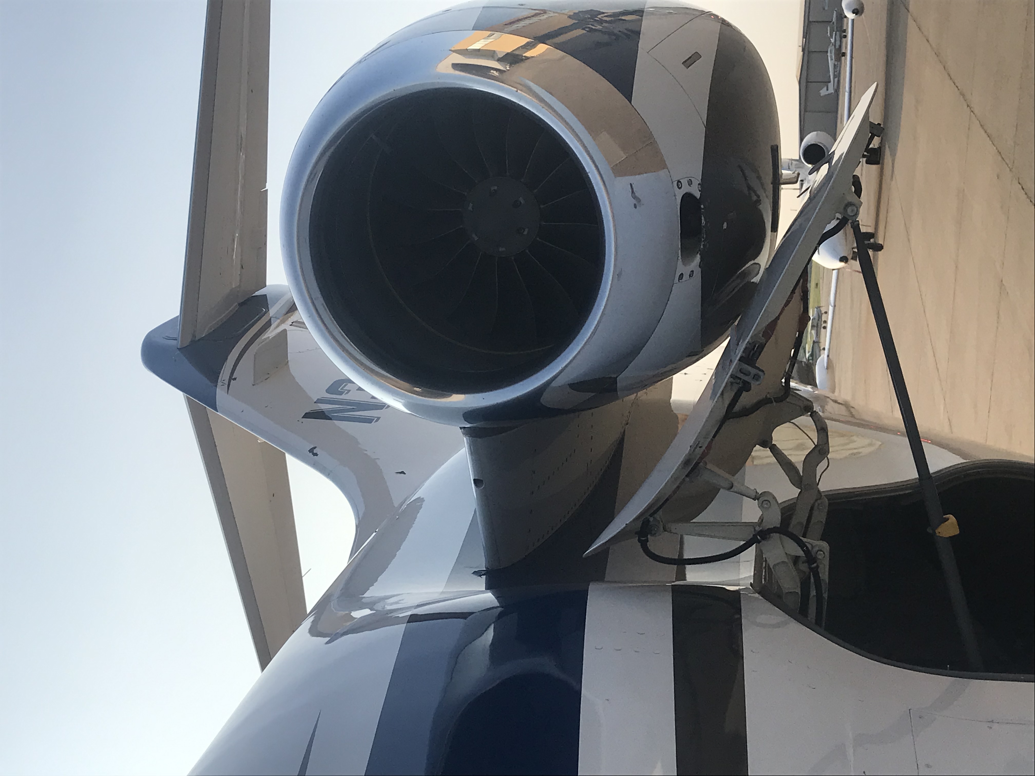 the front face of a turbofan engine nacele belonging to a parked business jet. the aircraft has its rear cargo door opened, the door sitting just below the engine